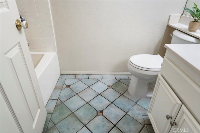 bathroom with baseboards, toilet, a tub, tile patterned floors, and vanity