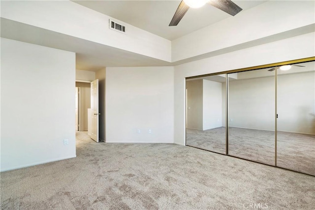 unfurnished bedroom featuring a closet, carpet flooring, visible vents, and a ceiling fan