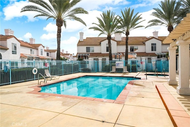 community pool with a residential view, a patio area, and fence