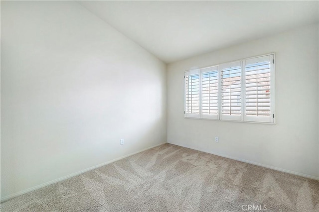 carpeted empty room featuring lofted ceiling