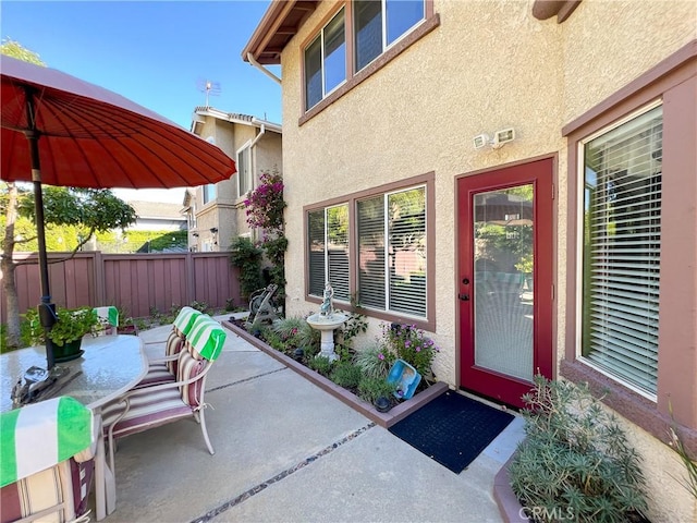 doorway to property featuring stucco siding, a patio, and fence