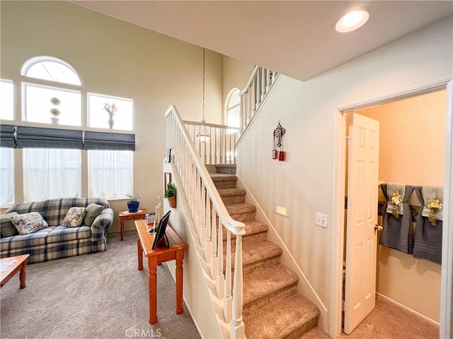 stairway with recessed lighting, baseboards, carpet floors, and a high ceiling