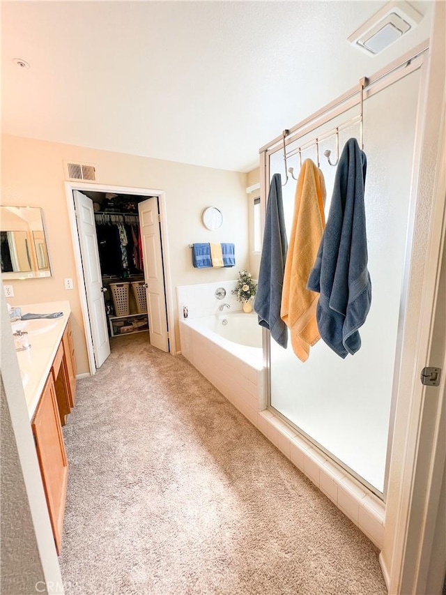 full bath with a spacious closet, visible vents, vanity, and a garden tub