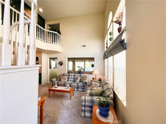 living area with a high ceiling, carpet, and visible vents