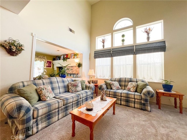 living room featuring visible vents, carpet flooring, and a towering ceiling