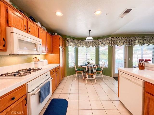 kitchen with light tile patterned floors, visible vents, white appliances, and tile counters