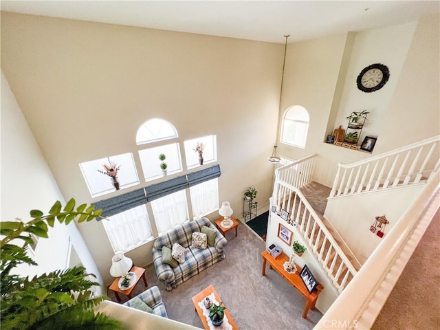 living room featuring a wealth of natural light, carpet, and a towering ceiling