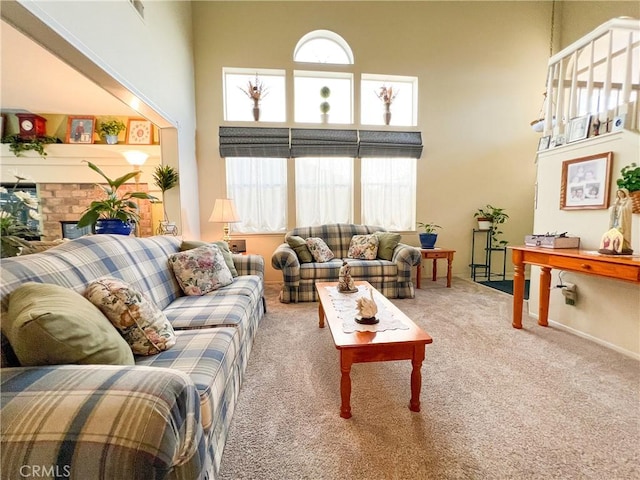 carpeted living area featuring a brick fireplace and a high ceiling