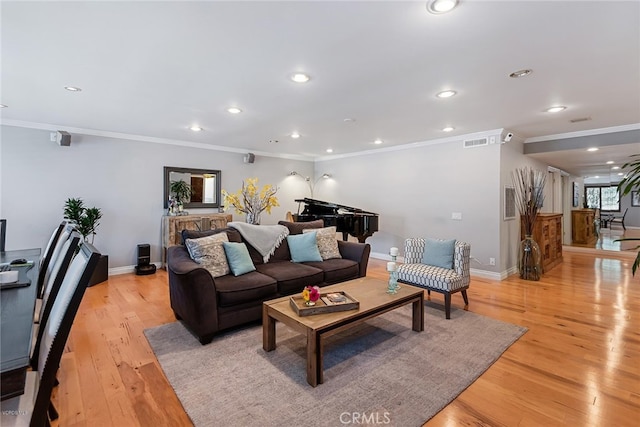 living room featuring visible vents, baseboards, ornamental molding, recessed lighting, and light wood-style floors