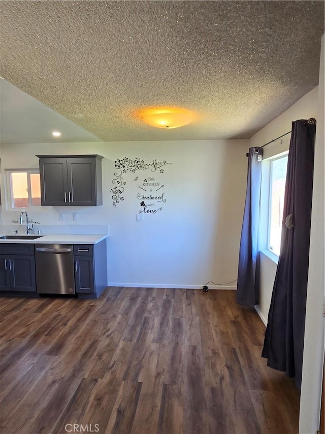 kitchen featuring stainless steel dishwasher, dark wood-style flooring, a sink, and a wealth of natural light