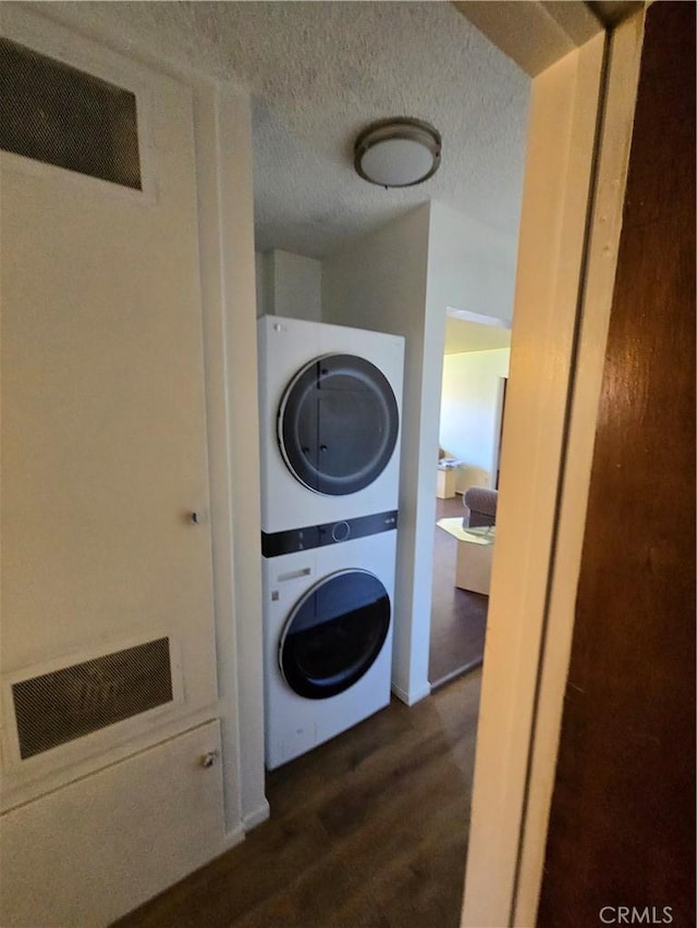 washroom with dark wood-type flooring, laundry area, visible vents, and stacked washing maching and dryer