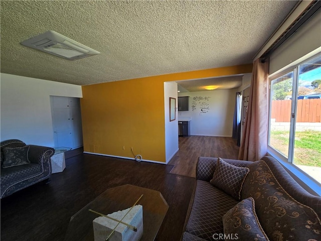 living room with a textured ceiling, baseboards, and wood finished floors