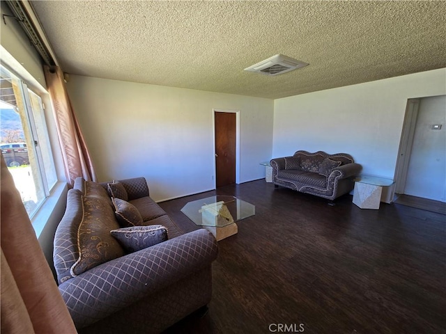 living room featuring visible vents, a textured ceiling, and wood finished floors