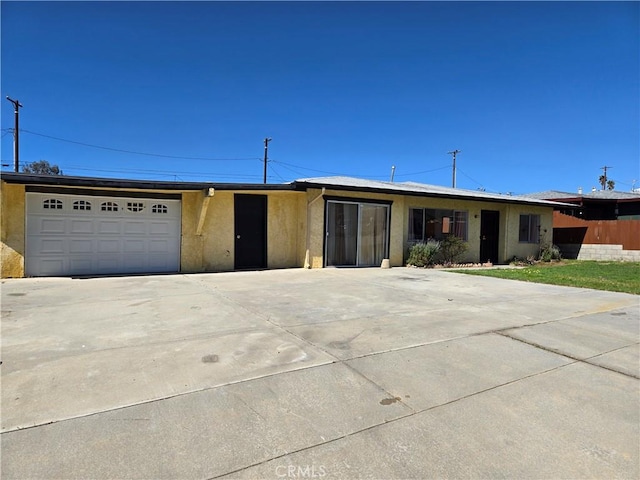 ranch-style house with a garage, fence, concrete driveway, and stucco siding