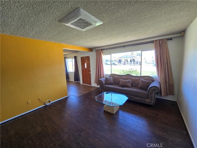 living area with a textured ceiling, visible vents, and wood finished floors