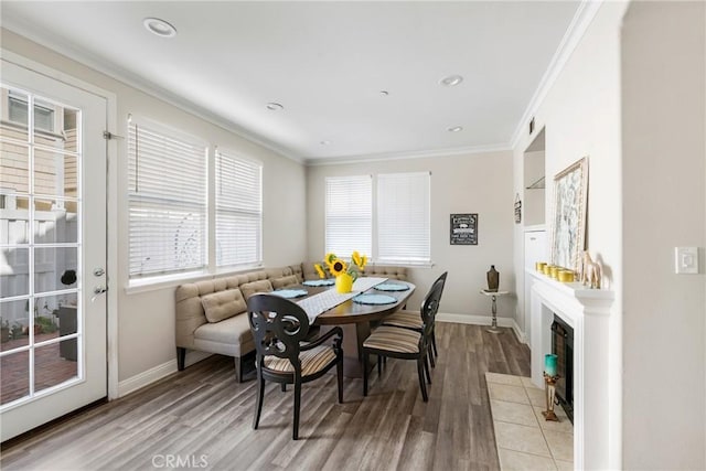 dining area featuring ornamental molding, light wood-style flooring, and a fireplace with flush hearth