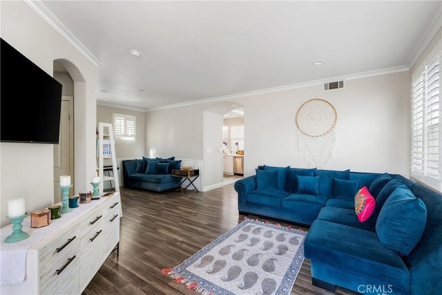 living area with dark wood-type flooring, arched walkways, visible vents, and ornamental molding