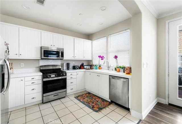 kitchen with visible vents, appliances with stainless steel finishes, light countertops, white cabinetry, and a sink