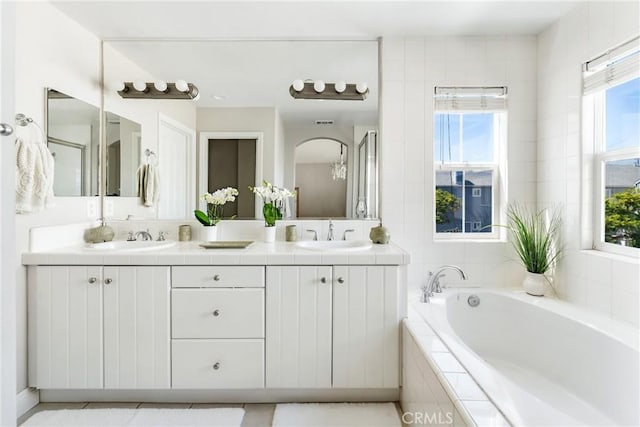 bathroom featuring double vanity, a garden tub, and a sink