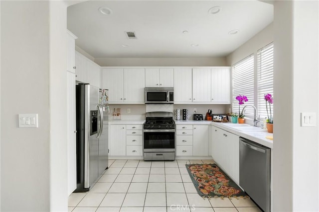 kitchen featuring light tile patterned floors, a sink, visible vents, light countertops, and appliances with stainless steel finishes