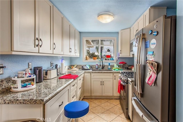 kitchen with stainless steel appliances, light stone counters, light tile patterned flooring, and a sink