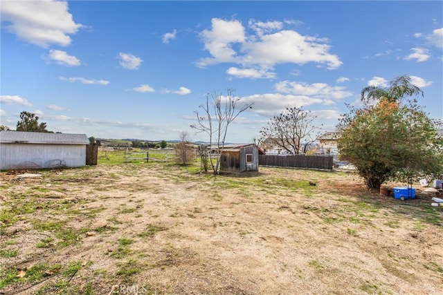 view of yard with a shed, fence, and an outbuilding