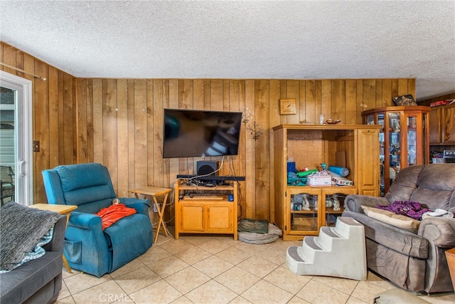 living area with light tile patterned floors, a textured ceiling, and wooden walls