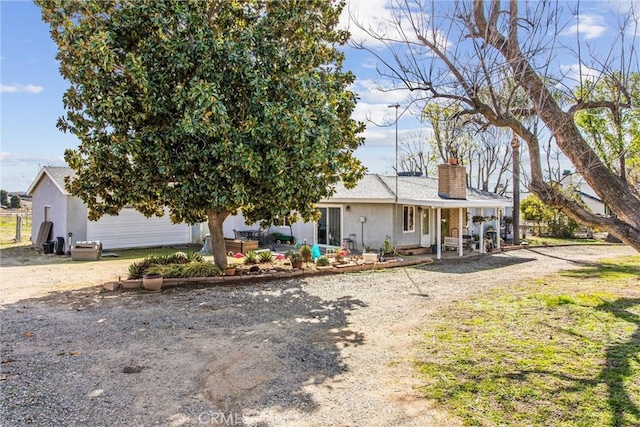 view of front of home featuring a patio area, a chimney, and stucco siding