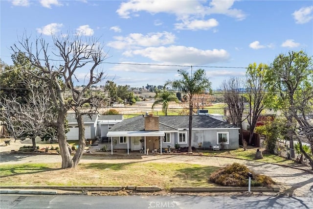 view of front of house featuring a front yard, driveway, and a chimney