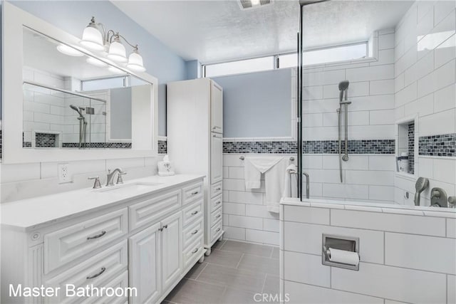 full bathroom featuring a stall shower, visible vents, tile patterned flooring, vanity, and tile walls