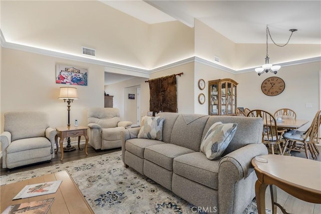 living area featuring high vaulted ceiling, wood finished floors, visible vents, and an inviting chandelier