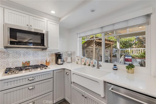 kitchen with a sink, decorative backsplash, stainless steel appliances, and a wealth of natural light