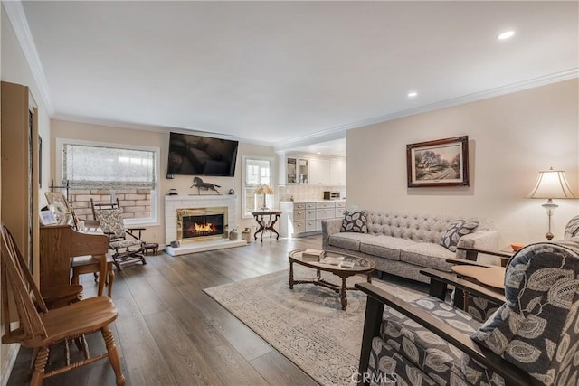 living room featuring recessed lighting, ornamental molding, dark wood finished floors, and a glass covered fireplace