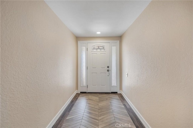 doorway featuring a textured wall and baseboards