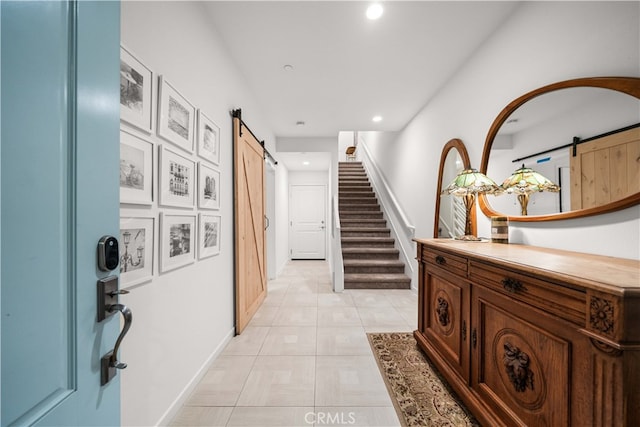 hall featuring light tile patterned floors, a barn door, stairs, and recessed lighting