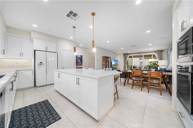 kitchen with stainless steel appliances, white cabinets, visible vents, and a kitchen island