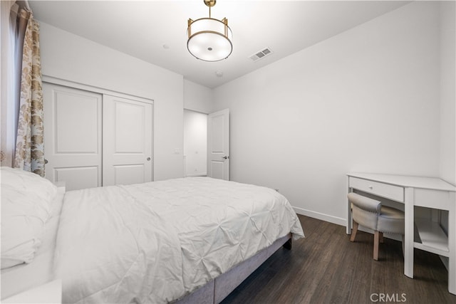 bedroom featuring baseboards, a closet, visible vents, and wood finished floors