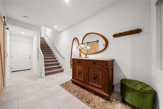 corridor featuring baseboards, a barn door, stairway, and recessed lighting