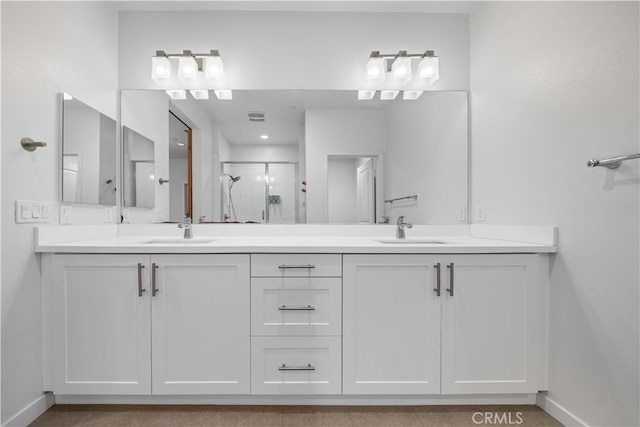 full bath with double vanity, a shower stall, baseboards, and a sink