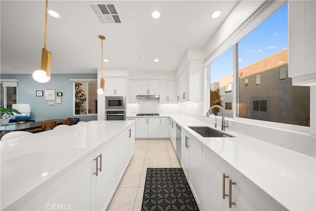 kitchen with under cabinet range hood, stainless steel appliances, a sink, visible vents, and light countertops