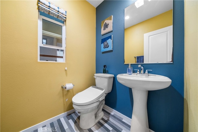 half bathroom with toilet, a sink, baseboards, and wood finished floors