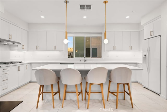 kitchen with white refrigerator with ice dispenser, visible vents, a sink, gas cooktop, and under cabinet range hood