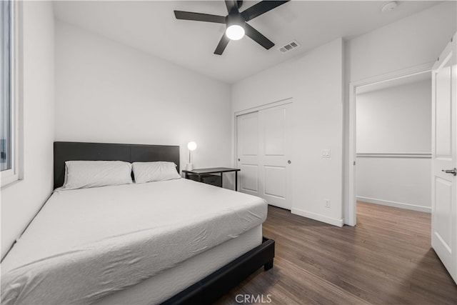 bedroom with baseboards, visible vents, a ceiling fan, wood finished floors, and a closet