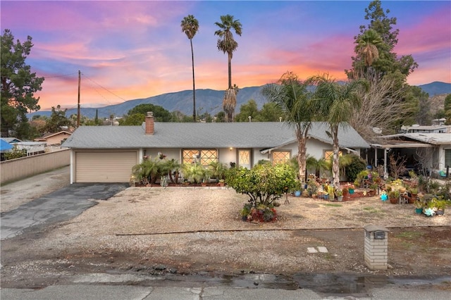 view of front of home with aphalt driveway, a mountain view, a chimney, and an attached garage