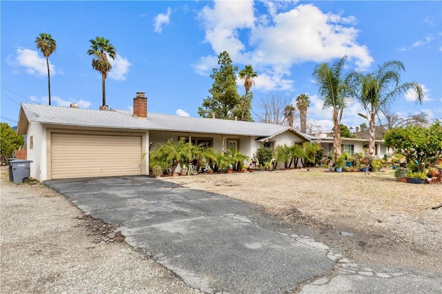 single story home featuring driveway, an attached garage, a chimney, and stucco siding