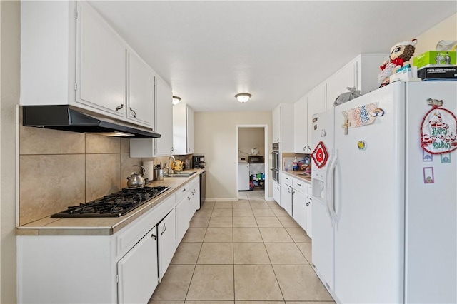 kitchen with light tile patterned flooring, under cabinet range hood, gas stovetop, light countertops, and white fridge with ice dispenser