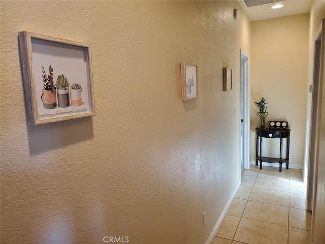 hallway featuring light tile patterned flooring and baseboards