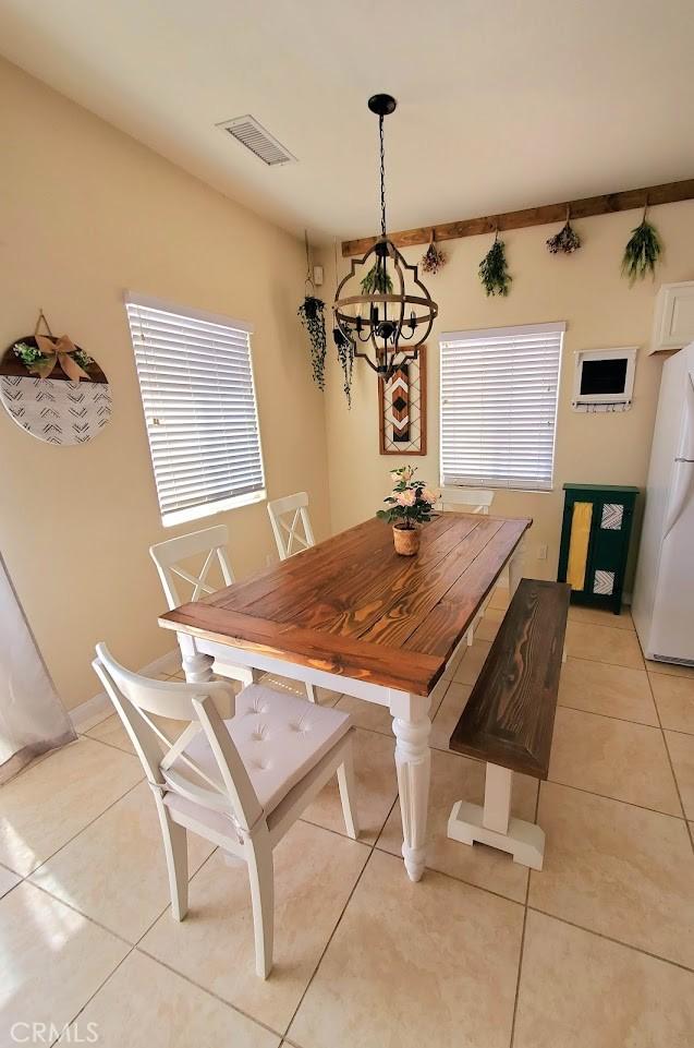 dining room featuring a chandelier, light tile patterned flooring, plenty of natural light, and visible vents