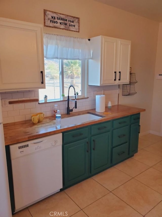 kitchen with light tile patterned flooring, a sink, white cabinets, backsplash, and dishwasher