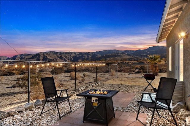 view of patio featuring a fire pit, fence, and a mountain view